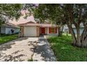 Charming single-story home featuring brick accents, a red front door, and mature trees in a well-maintained yard at 916 Glendale St, Orlando, FL 32807