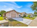 A view of a well-maintained single-story home with a spacious driveway and manicured lawn on a sunny day at 125 Owenshire Cir, Kissimmee, FL 34744