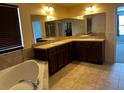 Bathroom featuring dual sinks, granite counters, tiled floors, large mirror, and a soaking tub at 12610 Sawgrass Oak St, Orlando, FL 32824
