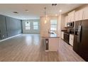 Open-concept kitchen with white cabinets, black appliances, gray countertops, and wood-look tile at 1308 Shinnecock Hills Dr, Davenport, FL 33896