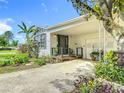 Charming front porch with covered parking, decorative plants, a black door, and white siding, for a welcoming entrance at 171 Stanley Bell Dr, Mount Dora, FL 32757