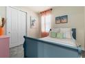 Cozy bedroom features a blue bed, carpet, and bright natural light from the window at 17335 Million Lakes Ct, Clermont, FL 34714
