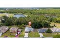 An aerial view of a home near a large pond and forested area, surrounded by other residences at 313 Greenwich Ct, Kissimmee, FL 34758