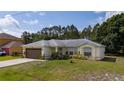 A well-maintained single-story home with lush green lawn, attached garage, and cozy front entrance at 313 Greenwich Ct, Kissimmee, FL 34758