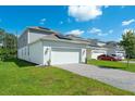 View of home's garage with solar panels installed on the roof, alongside a brick driveway and manicured lawn at 6328 Whip O Will Ln, St Cloud, FL 34771