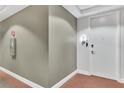 Hallway with neutral wall color and white trim leads to apartment entry door, safety instructions on the wall at 101 S Eola Dr # 810, Orlando, FL 32801