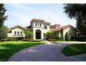 Stunning Mediterranean-style home with lush landscaping, tile roof, and a circular brick driveway leading to the grand entrance at 11013 Ullswater Ln, Windermere, FL 34786