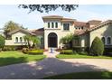 Elegant Mediterranean-style home featuring a tile roof, lush landscaping, and a circular driveway with a front water feature at 11013 Ullswater Ln, Windermere, FL 34786