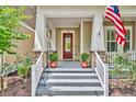 Close up of a inviting front porch with stone accents, classic columns, a stylish front door, and manicured landscaping at 1356 Coralstone Dr, Celebration, FL 34747