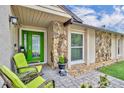Inviting porch with green door, stone accents, seating, and decorative plants at 150 Tarpon Cir, Winter Springs, FL 32708