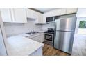 Well-lit kitchen with stainless steel appliances, marble countertops and backsplash, and wood flooring at 1507 Sw 4Th St, Ocala, FL 34471