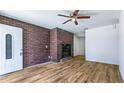 Cozy living room features a brick fireplace, wood-look flooring, and a ceiling fan at 1507 Sw 4Th St, Ocala, FL 34471