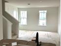 Bright living room area with staircase, two windows, and unfinished flooring at 15083 Grove Lake Dr, Winter Garden, FL 34787