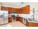 Modern kitchen with stainless steel appliances, cherry cabinets, and ample counter space for meal preparation at 4301 Heirloom Rose Pl, Oviedo, FL 32766