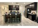 Spacious kitchen featuring dark cabinets, a large island with seating, and modern stainless steel appliances at 4427 Blackbird St, Kissimmee, FL 34746