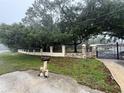 A stone and wrought iron gate with mature trees and landscaping providing privacy in this gated property at 4981 Lake Cecile Dr, Kissimmee, FL 34746