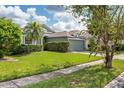 View of the manicured front lawn of the single story home with an attached two car garage at 9563 Myrtle Creek Ln, Orlando, FL 32832