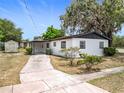 View of the home's exterior with a covered carport and additional storage shed, set against a clear blue sky at 1000 E Dixie Ave, Leesburg, FL 34748