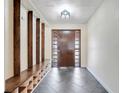 Inviting foyer featuring a front door with sidelights, tiled floor, and wooden bench with storage at 106 8Th St, Lake Hamilton, FL 33851