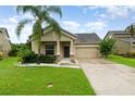 Charming single-Gathering home featuring a well-manicured lawn, two-car garage, and tropical landscaping at 1089 Seburn Rd, Apopka, FL 32703