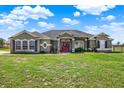 Charming single-story home featuring a red door, well-manicured lawn, and beautiful landscaping at 11115 Romance Ct, Winter Garden, FL 34787