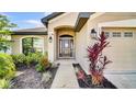 Inviting front entrance with well manicured landscaping, a black front door, and a two-car garage at 228 Bergamot Loop, Davenport, FL 33837