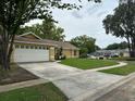 View of the yellow single-Gathering home showcasing the well-maintained lawn and extended driveway at 243 Country Landing Blvd, Apopka, FL 32703