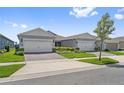 View of the home exterior featuring a two-car garage, manicured lawn, and tidy landscaping at 2960 Cherry Blossom Loop, St Cloud, FL 34771