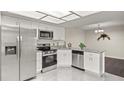 Modern kitchen featuring stainless steel appliances, granite countertops, white cabinets, and stylish, gray tile floors at 4643 Fern Pine Dr, Orlando, FL 32808