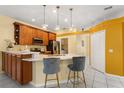 Well-lit kitchen with wooden cabinets, marble countertops, pendant lights, and modern bar stools at 507 Westwind Dr, Davenport, FL 33896