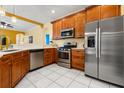 Spacious kitchen with stainless steel appliances, wooden cabinets, and white tile flooring at 507 Westwind Dr, Davenport, FL 33896