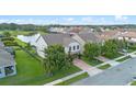 A beautiful aerial view of a two-story home with a lush green lawn and brick driveway near a pond at 646 Marsh Reed Dr, Winter Garden, FL 34787