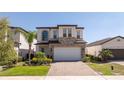 Charming two-story home with a brick driveway, featuring a two-car garage and manicured landscaping at 1311 Arisha Dr, Kissimmee, FL 34746