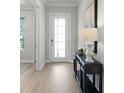 Bright entryway with light wood floors, console table, and a door with decorative glass panels at 13758 Tybee Beach Ln, Orlando, FL 32827