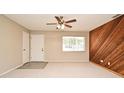 View of the living room, featuring a wooden accent wall, a ceiling fan, and plush carpeting at 1515 Pelican St, Longwood, FL 32750