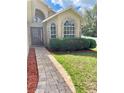 Beautiful front entrance with brick pathway, mulch landscaping, large window, and a storm door at 1980 Aquarius Ct, Oviedo, FL 32766