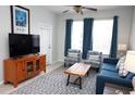 Bright living room features a blue sofa, patterned armchairs, a wooden coffee table, and neutral walls and tile flooring at 2785 Almaton Loop # 204, Kissimmee, FL 34747