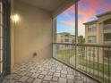 Relaxing screened patio with patterned tile floor, offering a serene view of the lush surroundings and beautiful colorful sunsets at 3000 Laurel Park Ln # 202, Kissimmee, FL 34741