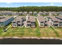 Aerial view of a neighborhood featuring gray two-story homes, green lawns, and a tranquil lake at 3039 Meleto Blvd, New Smyrna Beach, FL 32168