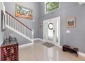 Bright foyer featuring tile flooring, a staircase with white railings, and a decorative wreath on the front door at 3063 Mandolin Dr, Kissimmee, FL 34744