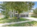 Traditional home with a well-manicured lawn, shade tree, and attached three car garage and inviting front door at 3063 Mandolin Dr, Kissimmee, FL 34744