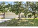 Traditional home with a two-car garage, lush lawn, and mature shade trees at 672 Reindeer Dr, Kissimmee, FL 34759