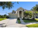 Charming one-story home featuring an arched entryway, a two-car garage, and lush, tropical landscaping at 7201 Halton Ct, Windermere, FL 34786