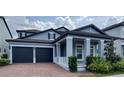 Charming two-story home featuring a brick driveway, lush landscaping, and a covered entryway with elegant columns at 9917 Summerlake Groves St, Winter Garden, FL 34787