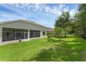 Expansive backyard features lush green grass, mature trees, and screened in porch perfect for relaxation and entertainment at 10125 Sandy Marsh Ln, Orlando, FL 32832