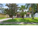 Inviting single-story home with red tile roof, offering curb appeal with its lush lawn and mature trees at 10169 Matchlock Dr, Orlando, FL 32821