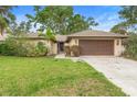 Inviting single-story home with a lush green lawn, mature trees, and a spacious driveway at 11 Huntley Ct, Haines City, FL 33844