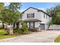 Charming home with grey shutters and a two-car garage, surrounded by lush landscaping and mature trees at 141 Dommerich Dr, Maitland, FL 32751
