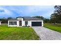 Inviting home showcasing a gray brick driveway, dark roof, manicured lawn and a modern facade at 16734 Sw 18Th Avenue Rd, Ocala, FL 34473
