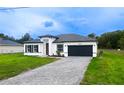 Beautiful single-Gathering home featuring a modern white and black design, attractive landscaping, and a gray driveway at 16734 Sw 18Th Avenue Rd, Ocala, FL 34473